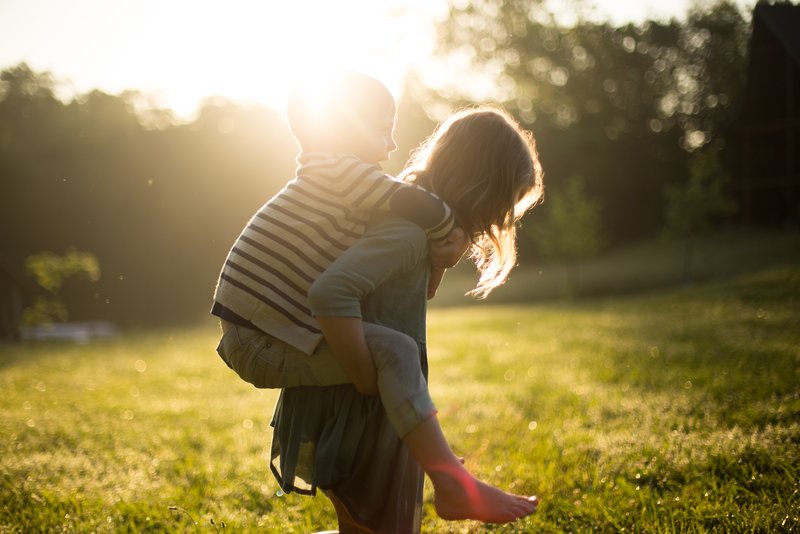 Mother carrying child across a field in the sunshine