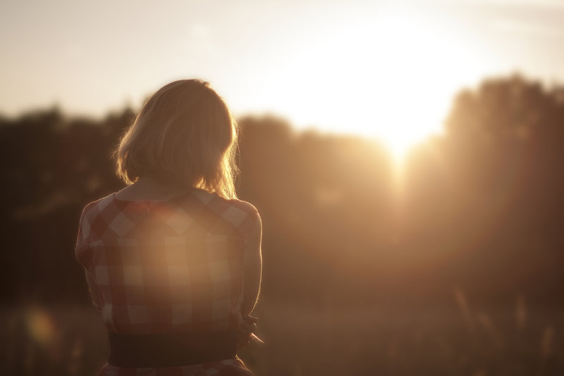 Girl standing alone in the sunset