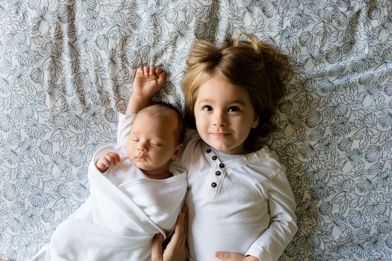 Child and baby lying on bed