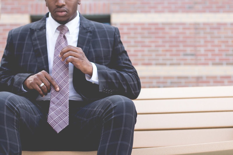 Man outside work adjusting his tie to reduce stress at work