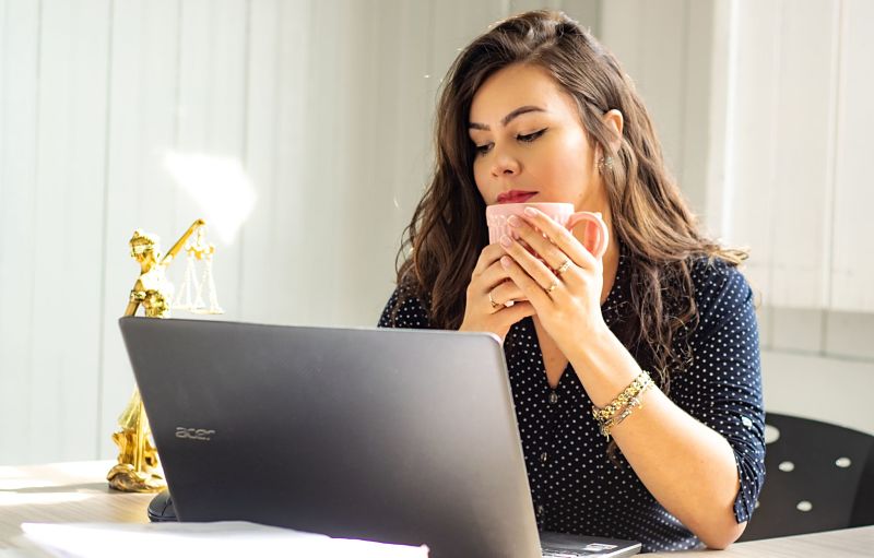 Woman drinking coffee on acer laptop