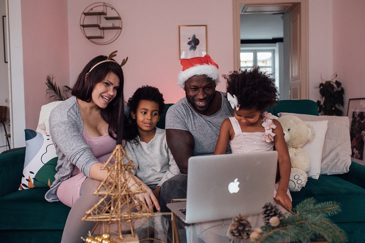 family sat around a macbook laptop celebrating a virtual christmas on video call