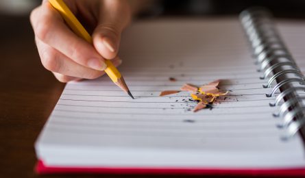 child writing in notebook with pencil ready to do back to school quiz