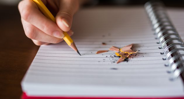child writing in notebook with pencil ready to do back to school quiz