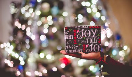 woman holding a festive gift under the christmas tree