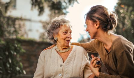 An elderly lady and a younger woman smiling at one another as they have funeral care cover