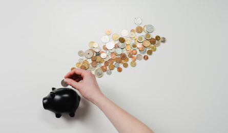 A piggy bank with various coins coming out of it.