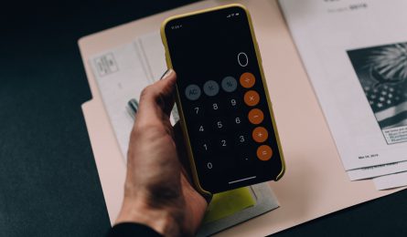 person using iphone calculator app for world financial planning day