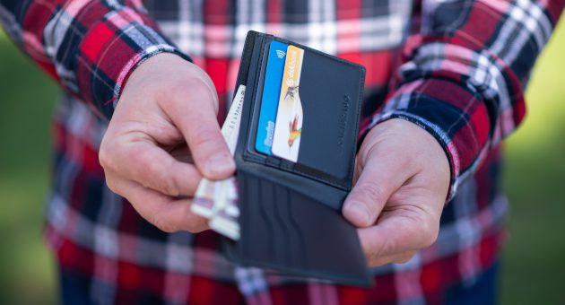 Hands opening a wallet with money and cards inside trying to learn how to stop spending money