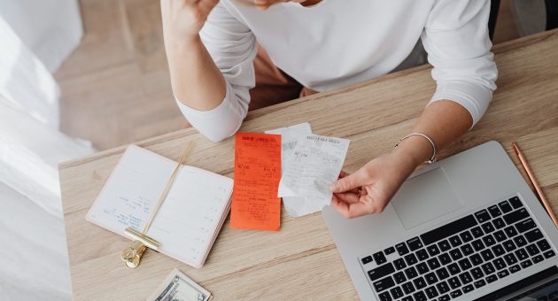 woman with her macbook looking at receipts and notes to improve her financial wellbeing